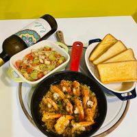 可能是西班牙大鍋飯、義大利麵、蝦和法式長棍麵包的圖像