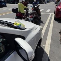 可能是 3 個人、停車計時器、電動滑板車、速克達、汽車和街道的圖像
