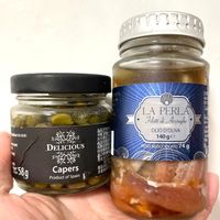 可能是鯷魚和顯示的文字是「 urtaende ende: DELICIOUS LA PERLA Filetti di Acciughe OLIOD'OLIVA OLIO D'OLIVA 140ge e 140 PESO SGOCCIOLATO PESOSGOCCIOLATO74g 74 و 58g Capers Product of Spain ProductofSpain أ 」 的圖像