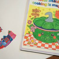 可能是顯示的文字是「 cooking PUIGO b, is magical! Enjoy every everyday day 倉 在食 STAUB 」的塗鴉