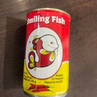 可能是鯷魚和顯示的文字是「 smiling Fish EWT. 3055oz) He $8(5.5 oz.) WT. WT.93g g 93 PRODUCT OF THALAND THAILAND NO.2031 」的圖像